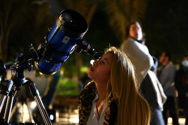 Una mujer mira a través de un telescopio en el techo del planetario distrital para ver un eclipse lunar en Bogotá, Colombia
