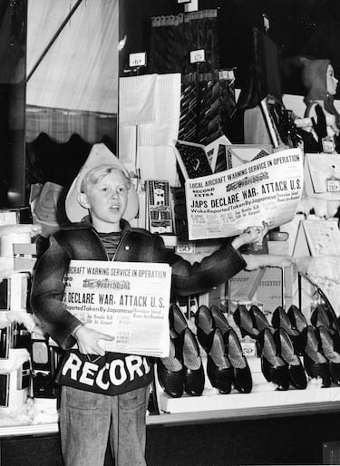 Un niño vende periódicos con el titular "Japoneses declaran la guerra y atacan a EE. UU." frente al escaparate de una tienda, en Redding, California.