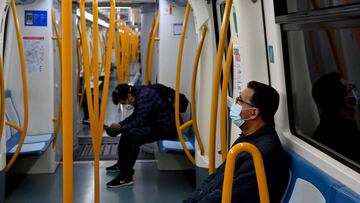Dos pasajeros viajan protegidos con mascarillas y guardando el distanciamiento social en un vag&oacute;n del Metro de Madrid.