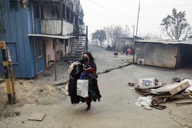 Una persona carga sus pertenencias mientras el fuego y el humo se elevan de un incendio forestal en la región del Biobío, donde, según medios locales, múltiples incendios forestales provocaron evacuaciones de emergencia, en Concepción, Chile.