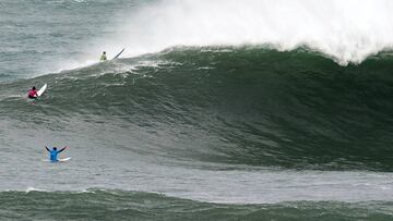 La ola gigante de La Vaca rompiendo durante la competici&oacute;n de La Vaca Gigante by Oakley 2019 en La Cantera-Cueto, Santander (Cantabria), mientras un surfista con licra azul levanta los brazos.