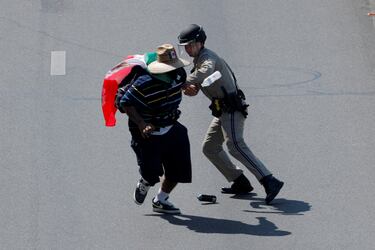 Un manifestante huye de un agente de la ley mientras intenta llegar a la autopista, durante una protesta contra las redadas federales de inmigración en el centro de Los Ángeles.