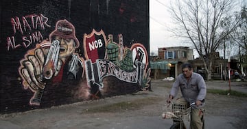 Un hombre pasea en biclieta al lado de un mural de ultras del Newell´s Old Boys.
