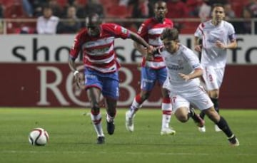 El defensa camerunés del Granada, Allan Romeo Nyom disputa un balón con el delantero del Sevilla, Denis Suarez.