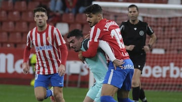 Los jugadores de la SD Huesca y el Real Sporting de Gijón luchan pugnan por el balón.