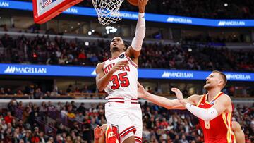 Oct 27, 2025; Chicago, Illinois, USA; Chicago Bulls forward Isaac Okoro (35) goes to the basket against Atlanta Hawks center Kristaps Porzingis (8) during the first half at United Center. Mandatory Credit: Kamil Krzaczynski-Imagn Images