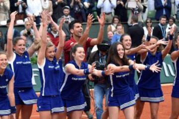 Novak Djokovic celebra con las recogepelotas su primera victoria en Roland Garros.