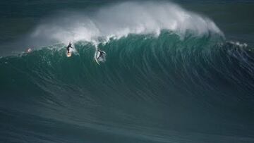 Un surfista sufriendo un wipeout y otro realizando el drop en una ola gigante en Praia do Norte (Nazar&eacute;, Portugal). 