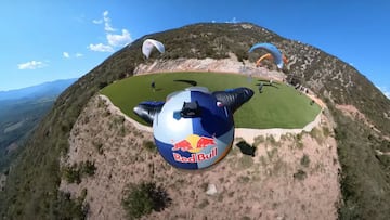El piloto de wingsuit Dani Román volando con su traje de alas en POV desde el casco sobre una zona de despegue de parapente en la montaña.