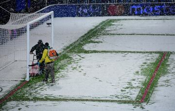 Operarios del club italiano quitan la nieve de las lineas del terreno de juego.