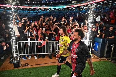 El exjugador del FC Barcelona Carles Puyol y el exmadridista Marcelo pasan sonrientes ante los numerosos medios de comunicación congregados en el Estadio Monumental Simón Bolívar de Caracas. Ambos estuvieron en la inauguración de la segunda edición de la Liga Monumental de Venezuela, representando a los equipos Cosa Nostra y Vergatarios FC.