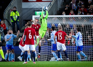 Earling Haaland observa como Unai Simón bloquea con sus manos un centro lateral del conjunto noruego.