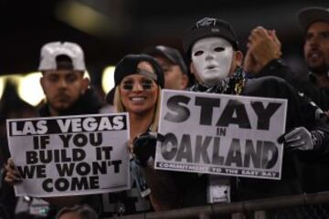Dos fans de los Raiders sostienen sendos carteles durante el encuentro contra los Broncos. El de la derecha reza "Quedaos en Oakland". El de la izquierda pone "Ya s¨¦ que mi amigo da miedete porque va en plan Michael Myers, pero va, quedaos, que no hace nada".