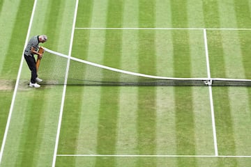 Un operario coloca un poste de la red antes de la final masculina del torneo de Wimbledon.