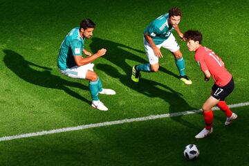 Los jugadores alemanes Jonas Hector y Sami Khedira persiguen a Lee Jae-Sung para conseguir el balón.
