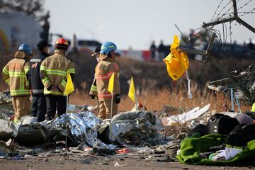 A life jacket hangs on fencing next to the wreckage of an aircraft.