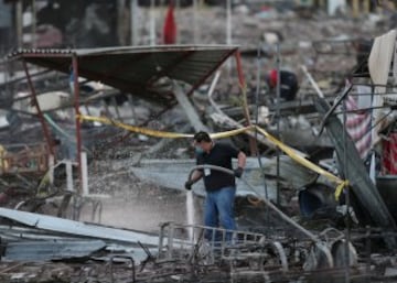 Un hombre arroja agua para garantizar que el fuego no se reaviva