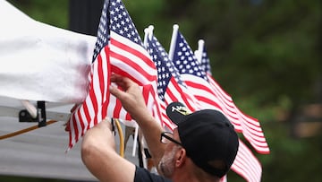 Hombre colgando varias banderas de Estados Unidos.