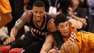 Damian Lillard y Devin Booker pugnan en el suelo por un bal&oacute;n.