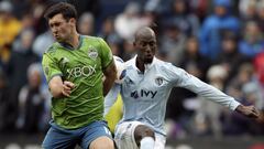 Seattle Sounders defender Will Bruin, left, blocks a kick by Sporting Kansas City defender Ike Opara, right, during the first half of an MLS soccer match in Kansas City, Kan., Sunday, April 15, 2018. (AP Photo/Orlin Wagner)