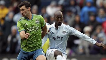 Seattle Sounders defender Will Bruin, left, blocks a kick by Sporting Kansas City defender Ike Opara, right, during the first half of an MLS soccer match in Kansas City, Kan., Sunday, April 15, 2018. (AP Photo/Orlin Wagner)