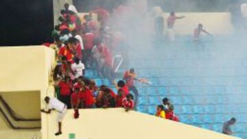 Aficionados se protegen de los gases lacrimógenos en una interrupción del juego en el partido entre Ghana y Guinea Ecuatorial.