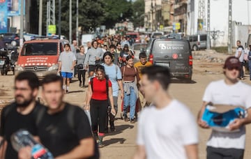 Varias personas caminan con bolsas y sus pertenencias en el barrio de La Torre en Valencia. 