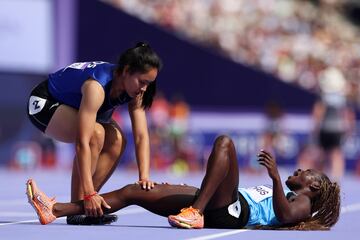 Lucia Moris del equipo de Sudán del Sur herida en el suelo mientras Silina Pha Aphay del equipo de la República Democrática Popular Lao verifica su estado durante la ronda preliminar de 100 m femenino.