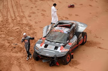 El piloto español de Audi, Carlos Sainz, habla por teléfono después de sufrir un accidente durante la novena etapa del Dakar. 

  