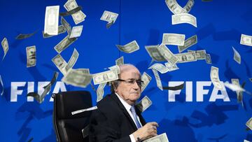 FIFA president Sepp Blatter looks on as fake dollar notes fly around him, thrown by a British comedian during a press conference at the FIFA world-body headquarter's in Zurich. -