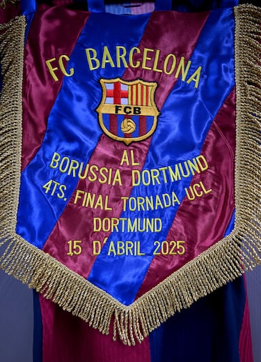 Vista general del banderín del partido, exhibido junto a una camiseta en el vestuario del FC Barcelona antes del partido de vuelta de cuartos de final de la UEFA Champions League 2024/25.