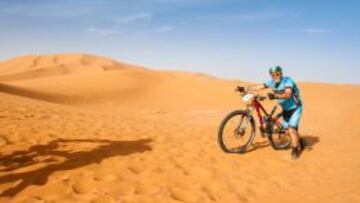 Juanito Oiarzabal, empujando su bicicleta en una duna. 