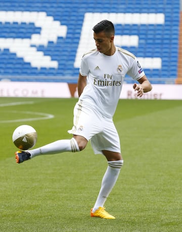 Reinier, vestido de blanco, posa para los medios en el césped del Santiago Bernabéu. 