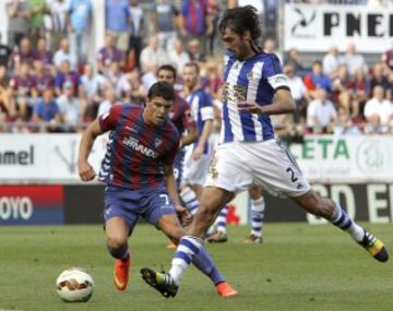 El defensa de la Real Sociedad Carlos Martínez (d) con el balón ante el centrocampista del Eibar Ander Capa (i) durante el partido de la primera jornada de Liga de Primera División, disputado esta tarde en el estadio de Ipurua.