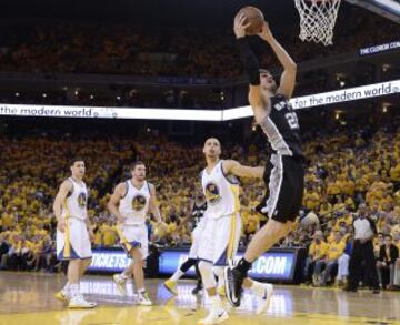 El jugador de los Spurs de San Antonio Tiago Splitter (dcha) entra a canasta ante la mirada de Stephen Curry (2º dcha), de los Warriors de Golden State, durante el sexto partido de la semifinal de la Conferencia Oeste disputado en el pabellón Oracle Arena de Oakland, Californa (Estados Unidos). Los Spurs ganaron por 82-94 para clasificarse para la final.