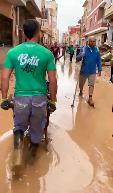 Un miembro de la peña del Betis 'Manque Pierda' de Elche, en las labores de limpieza en una localidad afectada por la DANA. 