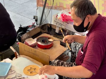 In this picture taken in Seoul on October 10, 2021, street vendor Lim Chang-joo stamps a star shape onto a dalgona,