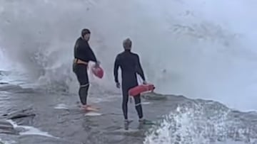 Dos socorristas a punto de entrar al agua entre olas gigantes que rompen contra las rocas en Windansea Beach, San Diego (California, Estados Unidos), en enero del 2023.