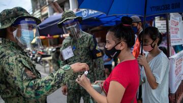 Police officers check a woman&#039;s quarantine pass at a checkpoint placed amid the reimposed strict lockdown to curb coronavirus disease (COVID-19) infections, in Manila, Philippines, August 17, 2020. REUTERS/Eloisa Lopez,