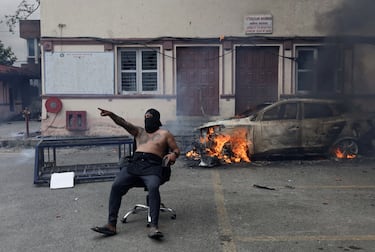 Un manifestante se sienta en una silla junto a un coche en llamas en la Corte Suprema durante una protesta contra el asesinato de 19 personas el lunes después de las protestas anticorrupción que se desencadenaron por una prohibición de las redes sociales, que luego se levantó, durante un toque de queda en Katmandú, Nepal.