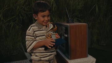 Imagen de un niño con camiseta a rayas sosteniendo un Premio Grammy dorado