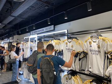 Clientes de la tienda oficial del Real Madrid viendo la primera equipación del club.