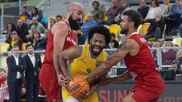 LAS PALMAS DE GRAN CANARIA, 16/12/2025.- El ala pívot tunecino del Benfica Ben Romdhane (i) y su compañero estadounidense Aaron Broussard presionan al alero colombiano del Dreamland Gran Canaria, Braian Angola (c), durante el partido de la sexta jornada de la Liga de Campeones de baloncesto que se disputa este martes en el Gran Canaria Arena. EFE/Quique Curbelo
