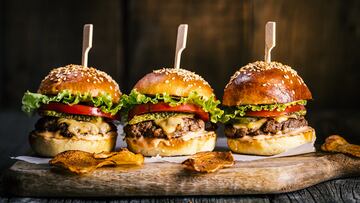 Cheeseburgers on wooden board and table in dark and moody light