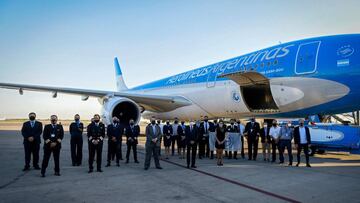 Handout photo released by the Argentinian Presidency of crew members and authorities posing next to an Aerolineas Argentinas airplane before its departure to bring 300,000 doses of the Sputnik V vaccine against covid-19 from Moscow, in Buenos Aires on December 22, 2020. - Argentina registers 42,254 deaths and over 1,5 million cases of covid-19. (Photo by Maria Eugenia CERUTTI / Argentinian Presidency / AFP) / RESTRICTED TO EDITORIAL USE - MANDATORY CREDIT AFP PHOTO / ARGENTINIAN PRESIDENCY / MARIA EUGENIA CERUTTI- NO MARKETING NO ADVERTISING CAMPAIGNS -DISTRIBUTED AS A SERVICE TO CLIENTS