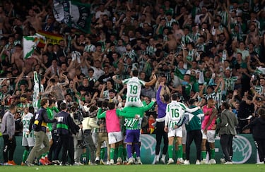Los jugadores y aficionados del Betis, celebran la victoria ante el Sevilla tras finalizar el partido en el estadio Benito Villamarín.