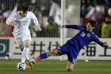 El delantero Yuya Osako (d), de la selección de Japón, pelea por el balón con el centrocampista Tim Payne (i), de Nueva Zelanda, durante el partido amistoso de fútbol que sus selecciones disputaron en el Estadio Nacional en Tokio.