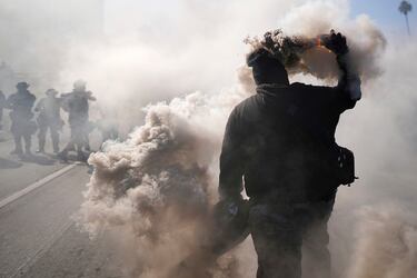 Un manifestante lanza una bomba de humo en la autopista 101, cerca del centro de detención metropolitano del centro de Los Ángeles.
