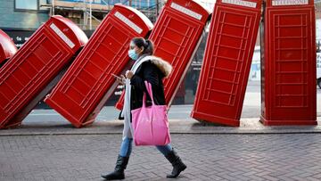 A shopper wearing a face covering to combat the spread of the coronavirus passes a piece of street art named 'Out of Order' by artist David Mach in the centre of Kingston upon Thames in south west London on January 9, 2022. - More than 150,000 people have died after catching coronavirus in the United Kingdom, the government said Saturday, in a tragic milestone for one of the worst affected countries in Europe. (Photo by Tolga Akmen / AFP) / RESTRICTED TO EDITORIAL USE - MANDATORY MENTION OF THE ARTIST UPON PUBLICATION - TO ILLUSTRATE THE EVENT AS SPECIFIED IN THE CAPTION