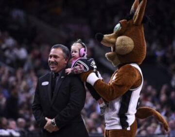 La mascota de los Cleveland Cavaliers,el Coyote, sostiene un bebé junto a un miembro del personal de seguridad durante un tiempo muerto del partido de la NBA entre los Cleveland Cavaliers y los San Antonio Spurs.